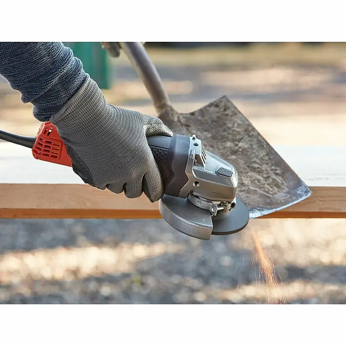 Black+Decker Elektro-Winkelschleifer BEG220-QS - 900 W, Durchmesser Scheibe: 125 mm, Leerlaufdrehzahl: 12.000 U/min - Winkelschleifer in Aktion: Eine Hand mit Handschuh schleift mit einer Flex eine Schaufel, Funken sprühen.
