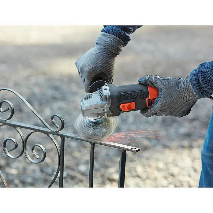 Black+Decker Elektro-Winkelschleifer BEG220-QS - 900 W, Durchmesser Scheibe: 125 mm, Leerlaufdrehzahl: 12.000 U/min - Ein Winkelschleifer in Aktion, der Metall bearbeitet und dabei Funken sprühen lässt, mit Schutzhandschuhen.
