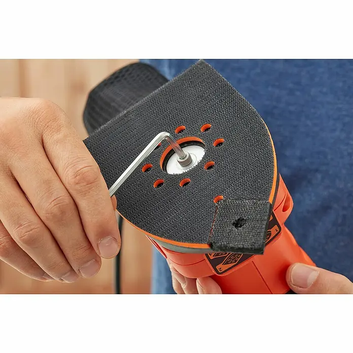 Black+Decker Elektro-Multischleifer BEW200K-QS - 200 W, Leerlaufschwingzahl: 24.000 U/min, Durchmesser Schwingkreis: 2 mm - Nahaufnahme eines Black+Decker-Elektrowerkzeugs, das mit einem Inbusschlüssel bearbeitet wird. Das Gerät ist orange und schwarz.