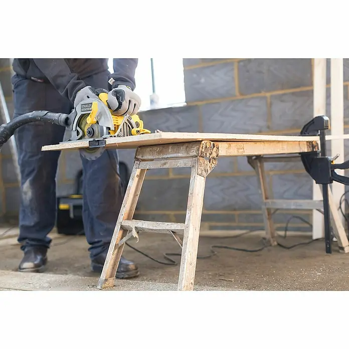 Stanley FatMax Handkreissäge FME301-QS - 1.650 W, Durchmesser Sägeblatt: 190 mm, Schnitttiefe bei 90 °: 66 mm - Ein Mann sägt ein Holzbrett mit einer Stanley Fatmax Kreissäge auf einer Werkbank. Das Werkzeug ist gelb und schwarz.