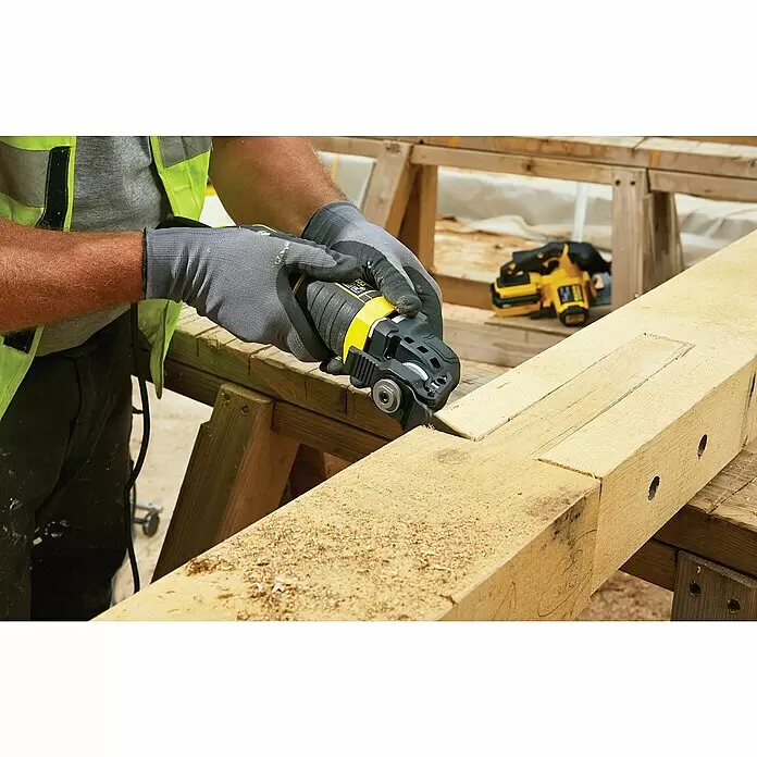 Stanley FatMax Elektro-Multifunktionswerkzeug FME650K-QS - 300 W, Sonstige - Eine Person benutzt ein gelb-schwarzes oszillierendes Multifunktionswerkzeug, um eine Kerbe in einen Holzbalken zu schneiden und Sägemehl zu erzeugen. Sie trägt graue Arbeitshandschuhe.