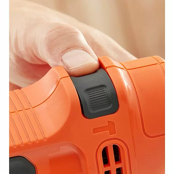 Black+Decker Schlagbohrmaschine BEH200K-QS - 500 W, Schnellspannbohrfutter - Ein Finger drückt einen schwarzen Schalter an einem orangefarbenen Elektrowerkzeug.