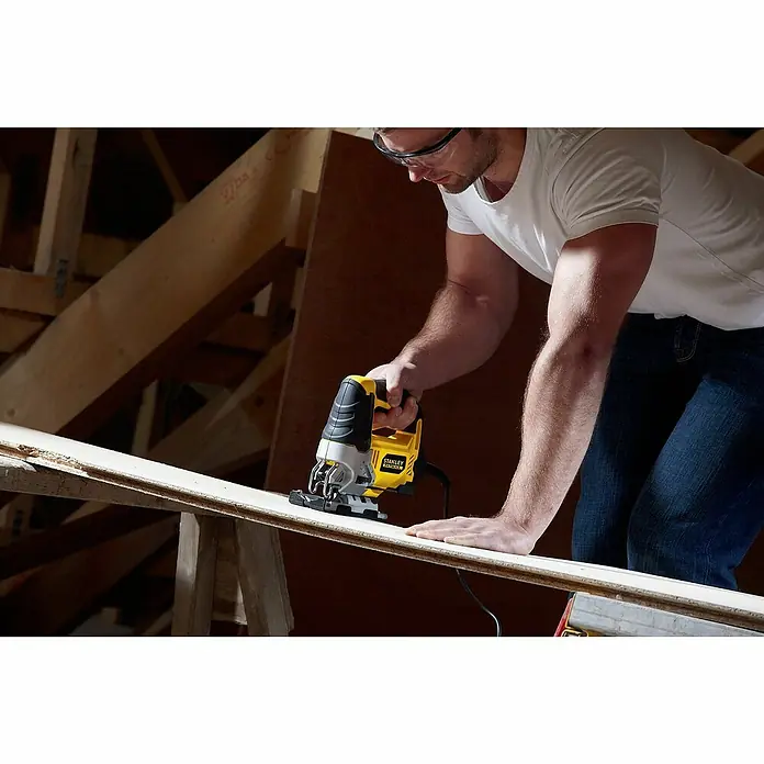 Stanley FatMax Elektro-Stichsäge FME340K-QS - 0 /min - 3.200 /min, 85 mm - Nahaufnahme einer Stanley Stichsäge in Aktion, während ein Mann ein Holzbrett bearbeitet, mit Fokus auf das Werkzeug.