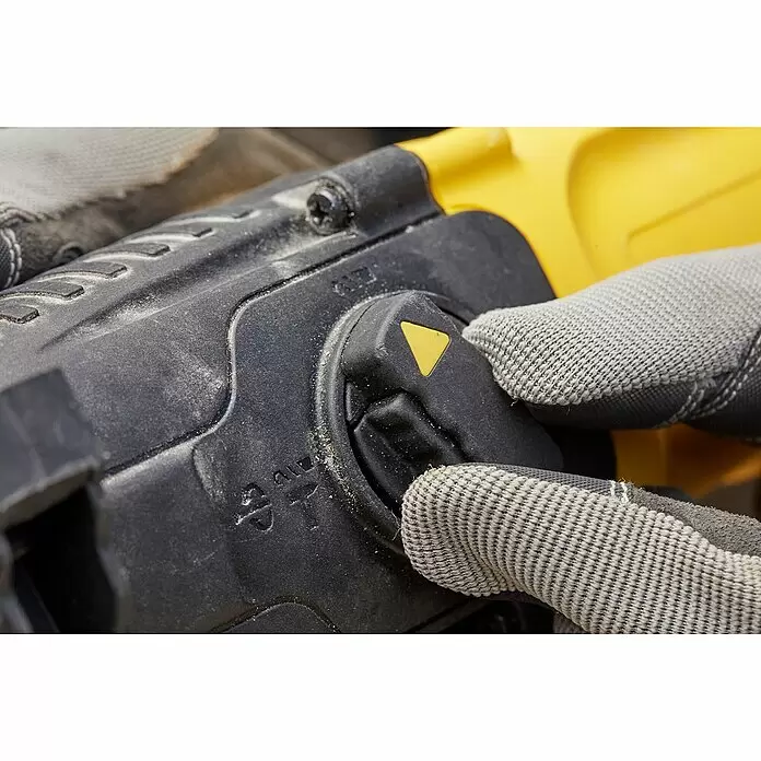 Stanley FatMax Kombihammer SFMEH210K-QS - 800 W, 2,4 J, SDS-Plus-Aufnahme - Nahaufnahme einer behandschuhten Hand, die den schwarzen Moduswahlschalter mit gelbem Indikator eines staubigen, schwarz-gelben Elektrowerkzeugs einstellt.