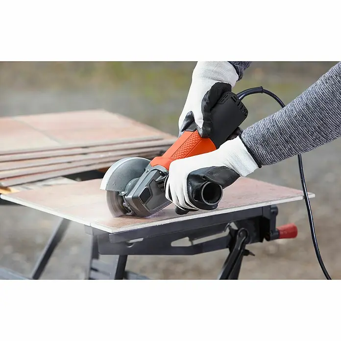 Black+Decker Elektro-Winkelschleifer BEG110-QS - 750 W, 115 mm - Bild einer Person, die mit einer Black+Decker-Flex eine Fliese schneidet. Die Flex ist orange mit schwarzen Akzenten.