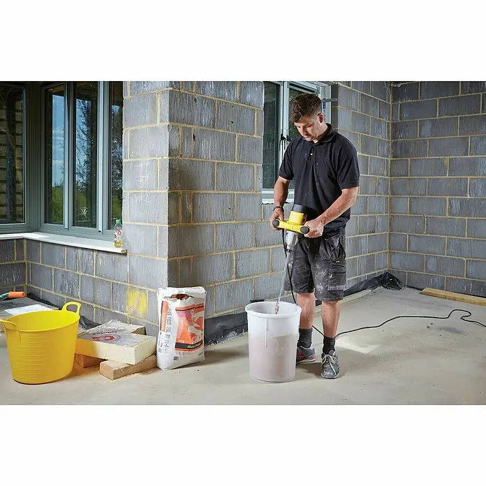 Stanley FatMax Farb- & Mörtelmischer FME190-QS - 1.600 W, Durchmesser Rührer: 150 mm, Mischvolumen: 120 l - Ein Mann benutzt einen Mörtelrührer, um in einem Eimer eine Mischung anzurühren. Gut für Bauprojekte, die eine homogene Masse erfordern.