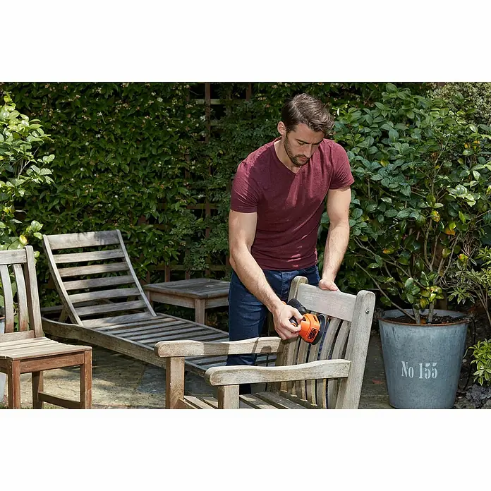 Black+Decker Elektro-Multischleifer BEW200K-QS - 200 W, Leerlaufschwingzahl: 24.000 U/min, Durchmesser Schwingkreis: 2 mm - Mann schleift einen Holzstuhl mit einem BLACK+DECKER Schleifer im Garten. Perfekt für die Möbelrestaurierung im Freien.