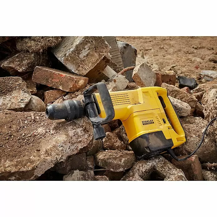 Stanley FatMax Abbruchhammer SFMEH230K-QS - 1.600 W, 15 J, SDS-Max-Aufnahme - Gelber und schwarzer Stanley FatMax Abbruchhammer liegt auf einem Haufen Beton- und Ziegelbruch.