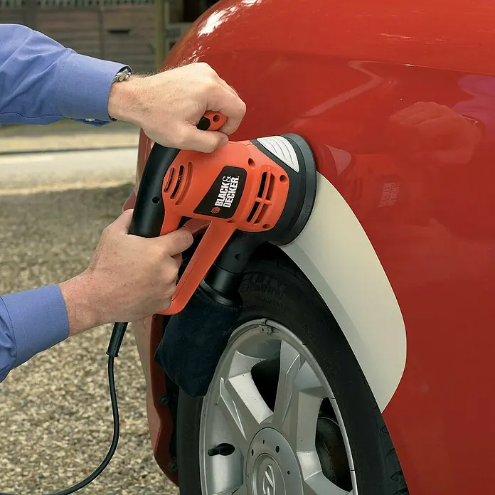 Black+Decker Exzenterschleifer KA191EK-QS - 480 W, Durchmesser Schleifteller: 125 mm - Nahaufnahme eines Mannes, der mit einer Black+Decker Poliermaschine an einem roten Auto arbeitet, um den Lack zu polieren.
