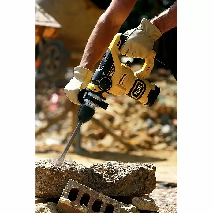 Stanley FatMax Kombihammer FME1250K-QS - 1.250 W, 3,5 J, SDS-Plus-Aufnahme - Eine Person mit Handschuhen verwendet einen gelb-schwarzen Stanley Fatmax Bohrhammer zum Meißeln von Beton.