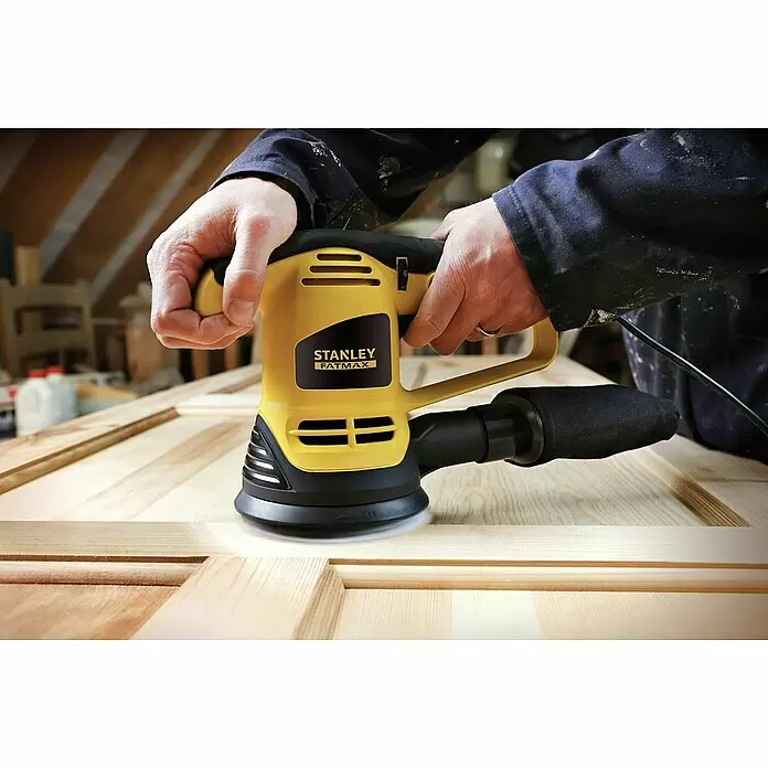Stanley FatMax Elektro-Exzenterschleifer FME440K-QS - 480 W - Eine Person nutzt einen gelb-schwarzen Stanley FatMax Exzenterschleifer, um eine Holztür oder -platte zu glätten.