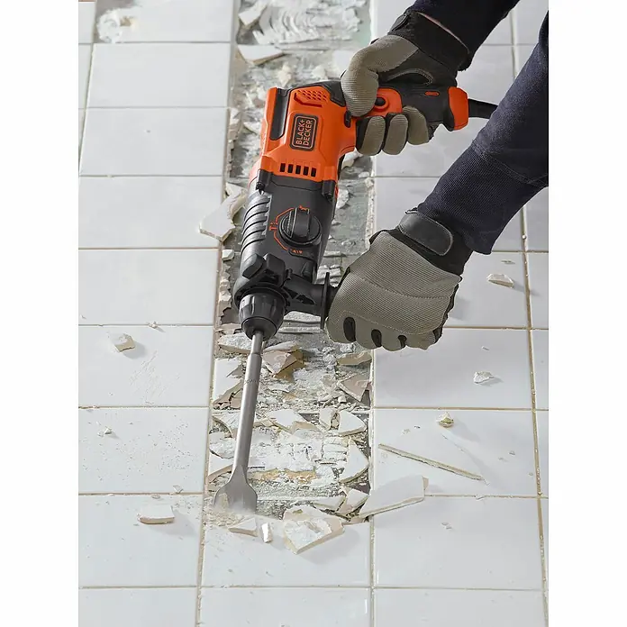 Black+Decker Kombihammer BEHS01K-QS - 650 W, 1,4 J, SDS-Plus-Aufnahme - Nahaufnahme eines Black+Decker Bohrhammers, der zum Entfernen von Fliesen verwendet wird. Die Maschine wird mit Handschuhen bedient.