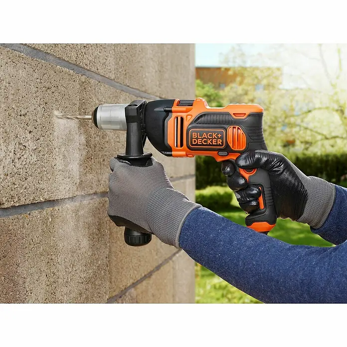 Black+Decker Schlagbohrmaschine BEH850K-QS - 850 W, Leerlaufdrehzahl 1. Gang: 3.100 U/min, Max. Schlagzahl: 54.400 /min - Aufnahme einer Black+Decker Schlagbohrmaschine in Aktion, die ein Loch in eine Ziegelmauer bohrt, mit dem Fokus auf Leistung.