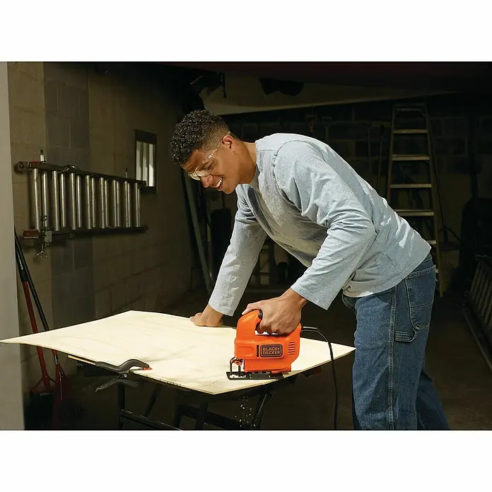 Black+Decker Elektro-Stichsäge KS501-QS - 3.000 /min, 65 mm - Ein Mann benutzt eine BLACK+DECKER Stichsäge, um Holz zu schneiden. Die orangefarbene Stichsäge ist ein Blickfang.