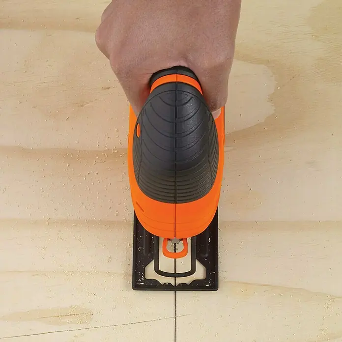 Black+Decker Elektro-Pendelhubstichsäge KS701PEK-QS - 3.000 /min, Max. Schnitttiefe in Holz: 70 mm, Anzahl Pendelhubstufen: 4 Stk. - Eine orangefarbene Stichsäge schneidet präzise durch ein helles Holzbrett, geführt von einer Hand. Ideal für Heimwerkerprojekte.