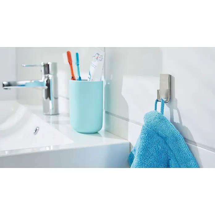 Tesa Powerstrips Selbstklebehaken - Rechteckig, Größe: S, Metallic, 2 Stk. - Eine Nahaufnahme eines Badezimmers mit einem blauen Handtuch, das an einem Haken hängt, einer Zahnbürste und einer Spüle.