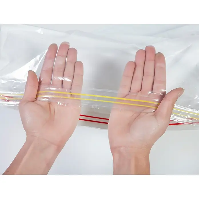 Set de bolsas de vacío HousyBags™ - 12 ud., Transparente - Primer plano de una bolsa transparente con cierre de cremallera sostenida abierta por manos, ideal para guardar varios objetos.