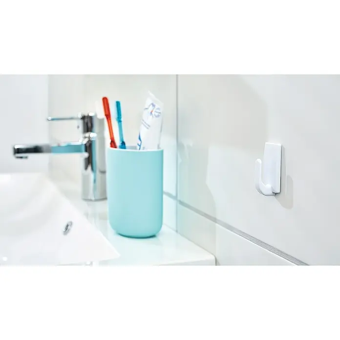 Tesa Powerstrips Selbstklebehaken - Eckig, Größe: S, Weiß, 3 Stk. - Nahaufnahme eines Badezimmers mit einem weißen Haken an der Wand und einem blauen Becher mit Zahnbürsten.