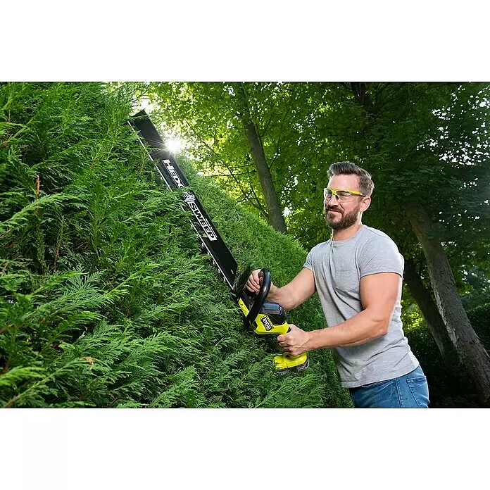 Ryobi ONE+ Akku-Heckenschere RY18HTX60A-0 - 18 V, Li-Ionen, Ohne Akku, Schwertlänge: 60 cm - Mann trimmt eine grüne Hecke mit einem schwarz-gelben Akku-Heckenschneider mit „HEDGE SWEEP“ Laubsammler.