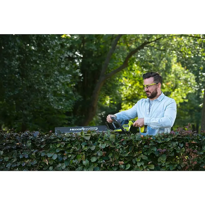 Ryobi ONE+ Akku-Heckenschere RY18HT55A-0 - 18 V, Li-Ionen, Ohne Akku, Schwertlänge: 55 cm - Ein Mann, der eine Ryobi Heckenschere benutzt, um eine Hecke zu schneiden. Die Heckenschere ist das Hauptprodukt im Bild.