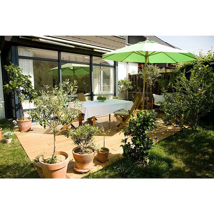 Elephant Terrassendiele - Bambus, 300 x 14 x 2 cm, Beige - Sonnige Gartenszene mit einladender Terrasse, Tisch mit Stühlen, Sonnenschirm und üppigen Pflanzen in Töpfen.