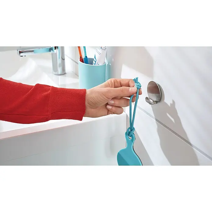Tesa Powerstrips Selbstklebehaken - Rund, Größe: S, Metallic, 2 Stk. - Hand hängt einen blauen Gegenstand mit einer Schnur an einen runden, silbernen Haken an einer Badezimmerwand.