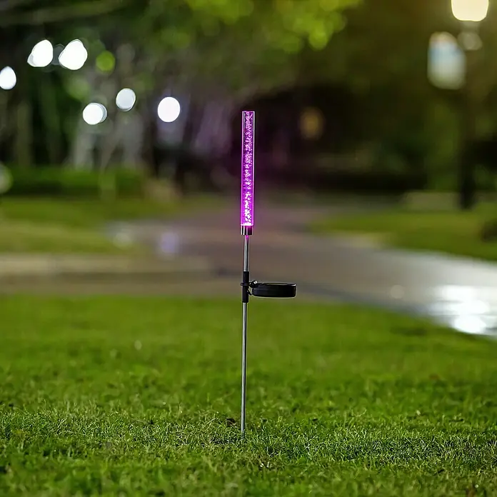 BAUHAUS Lámpara decorativa solar Bubble - 0,06 W, Transparente, IP44 - Primer plano de una luz solar con detalles morados en el jardín. La lámpara decorativa es llamativa y crea ambiente.