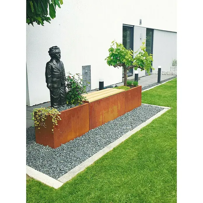Palatino Sitzdeckel Lotte - 120 x 40 cm, Passend für: Palatino Exlusive Line Pflanzkübel eckig Lotte 120 x 40 cm, WPC - Ein dekorativer Außenbereich mit einer Pflanzbank aus Cortenstahl, akzentuiert durch eine Statue und umgeben von grünem Rasen.