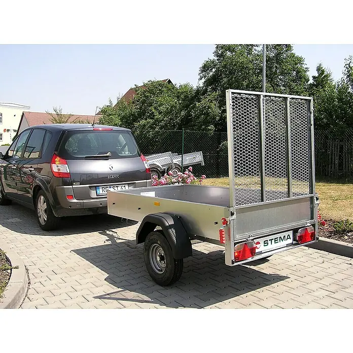 Stema Anhänger Green Keeper 750 mit Hochplane - Nutzlast: 588 kg, Einachser, Kasteninnenmaß: 201 x 108 x 26,5 cm, Ungebremst - Silberner STEMA Anhänger hinter einem grauen Renault Scenic, der auf einem gepflasterten Bereich steht.