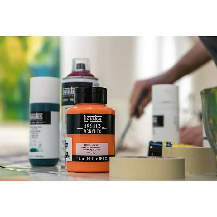Liquitex Basics Acrylfarbe - Ungebleichtes Titan, 400 ml - Nahaufnahme einer Flasche Liquitex Basics Acrylfarbe in Kadmiumorange, umgeben von weiterem Malzubehör.