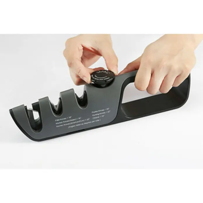 Afilador Premium - Específico para: Tijeras, cuchillos y navajas - Una persona ajusta un afilador de cuchillos ajustable en gris, sobre una superficie blanca.