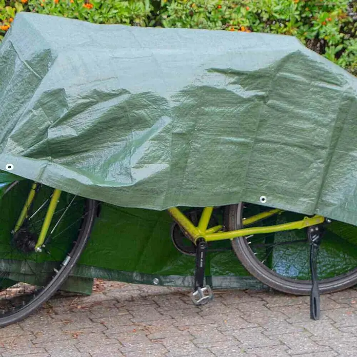 Kaminholz-Abdeckplane - 6 x 1,5 m - Ein gelbes Fahrrad ist mit einer grünen Plane abgedeckt, die es vor Witterungseinflüssen schützt. Perfekt für den Schutz vor Regen und Staub.