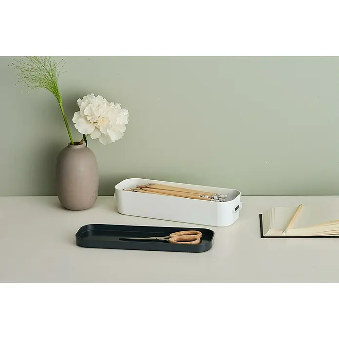 SmartStore Deckel Compact - L x B x H: 28,9 x 9,8 x 1,9 cm, Kunststoff, Schwarz - Stillleben mit einem grauen Krug und einer einzelnen weißen Blume, einer weißen Stiftablage und einer dunklen Schale mit einer Schere auf dem Schreibtisch.