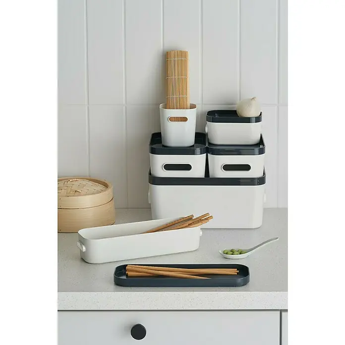 SmartStore Aufbewahrungsbox Compact - L x B x H: 9,8 x 9,4 x 10,2 cm, Kunststoff, Weiß - Küchenutensilien-Set: weiße und dunkelgraue Behälter für Stäbchen, Löffel, Knoblauch und Bambusmatte auf einer Küchentheke.