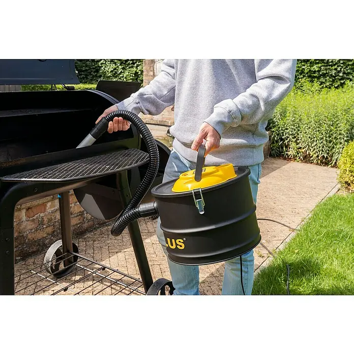 PowerPlus Aspirador de cenizas eléctrico POWX3000 - 1.000 W, Volumen de recipiente: 15 l, Sin bolsa - Alguien limpia una parrilla con un aspirador de cenizas negro y amarillo, mostrando el aspirador de cenizas en uso.