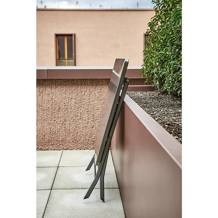 Sunfun Balkonmöbel-Set Maja/Eva - 3 -tlg., Stahl, Aluminium/Rattan, Anthrazit/Schwarz/Natur - Zusammengeklappter Tischlehnt an einer Wand auf einer Terrasse. Das schlanke Design des Tisches ist modern und platzsparend.