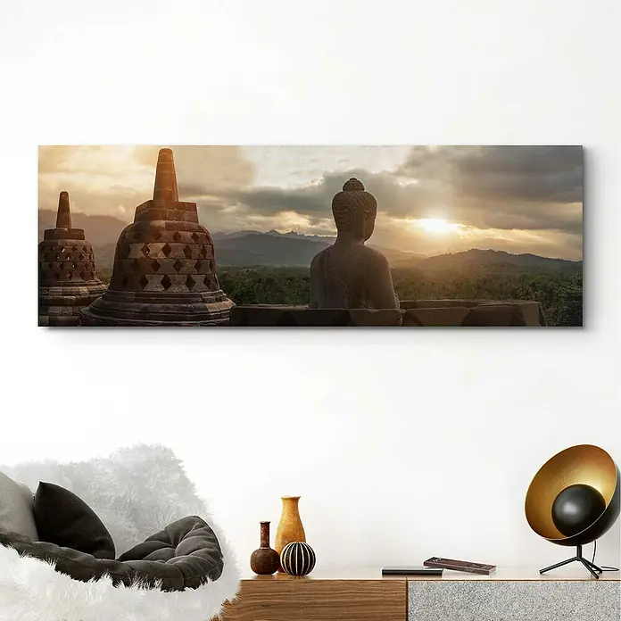 Reinders Decopanel - Borobudur, B x H: 156 x 52 cm - Wandbild mit einer Buddha-Statue und Tempeln bei Sonnenuntergang, das eine friedliche Atmosphäre in den Raum bringt.