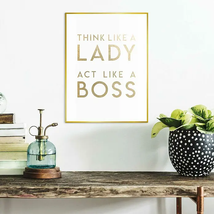 Reinders Bild Slim Frame Gold - Lady Boss, B x H: 30 x 40 cm - Dekoratives Bild mit Goldrahmen und Schriftzug "Think like a lady, act like a boss", neben einer Pflanze und einem Sprühgerät auf einem rustikalen Tisch.