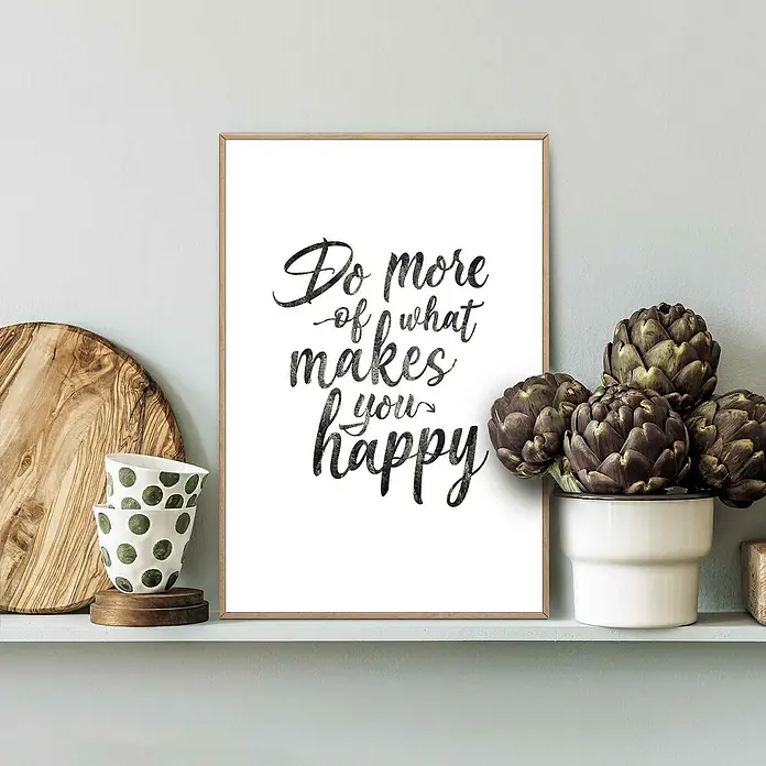 Reinders Bild Slim Frame Wood - Do More, B x H: 20 x 30 cm - Ein dekoratives gerahmtes Poster mit dem inspirierenden Zitat "Do more of what makes you happy" auf einem weißen Regal, neben Pflanzen und Geschirr.
