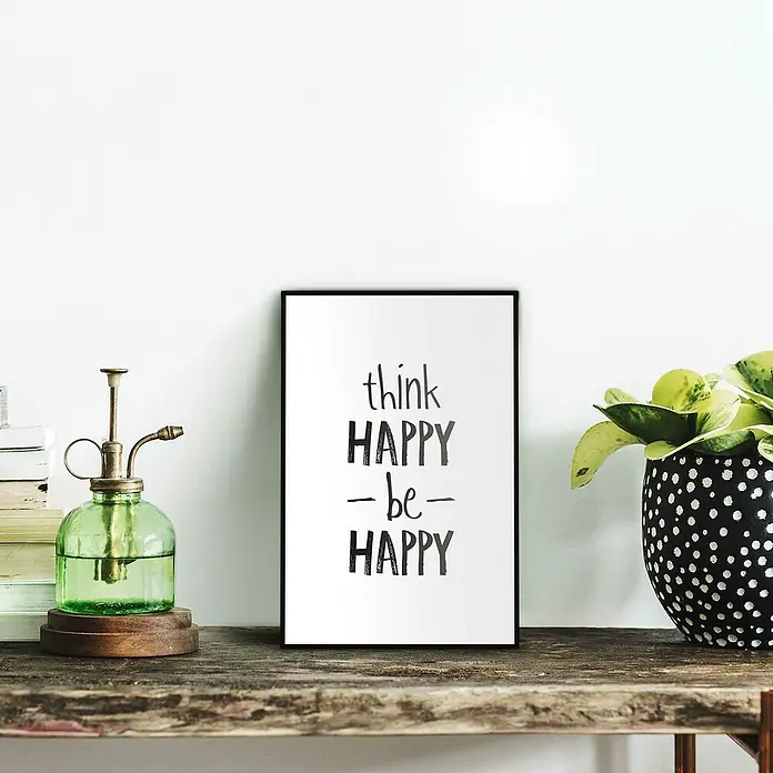 Reinders Bild Slim Frame BlackThink Happy, B x H: 20 x 30 cm - Dekoratives Schwarz-Weiß-Poster mit der Aufschrift "think HAPPY – be – HAPPY", neben einem grünen Wassersprüher und einer Pflanze mit getupftem Topf.