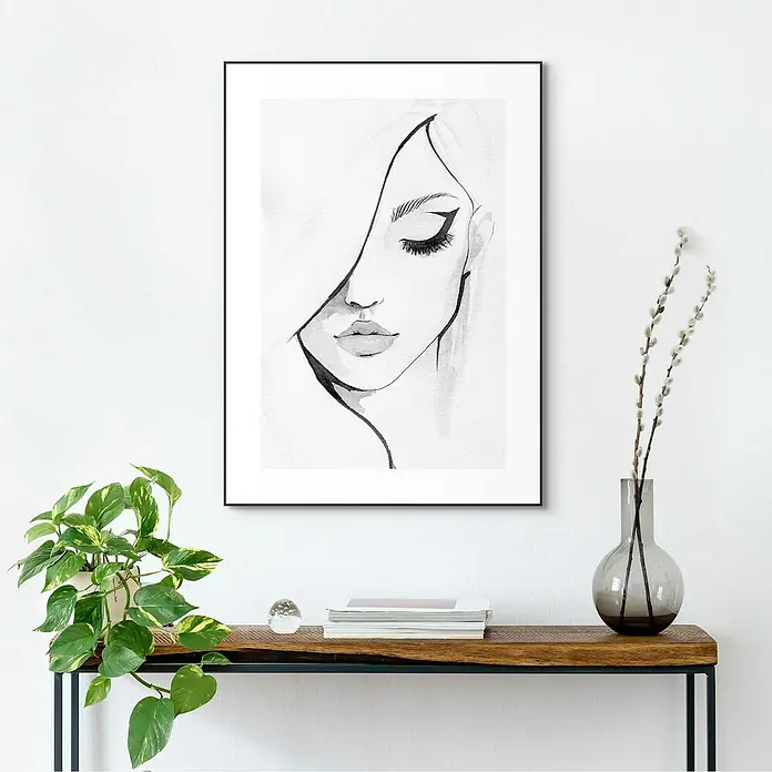 Reinders Bild Slim Frame Black - Female, B x H: 50 x 70 cm - Elegantes gerahmtes Wandbild, das eine stilisierte Frauengesichtsskizze zeigt, aufgehängt über einem Holztisch mit Deko-Elementen.