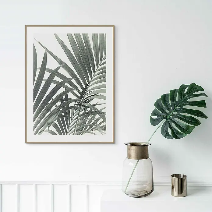Reinders Bild Slim Frame WoodPalm Leafs, B x H: 30 x 40 cm - Ein stilvolles Bild mit einem gerahmten Pflanzenmotiv und einer dekorativen Vase mit Blatt auf einem weißen Tisch.