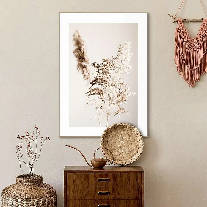 Reinders Bild Slim Frame WoodShadow Grass, B x H: 50 x 70 cm - Ein Arrangement aus einem gerahmten Pflanzendruck, einem Holztisch mit Deko-Elementen und einer Makramee-Wanddekoration in warmen Farbtönen.