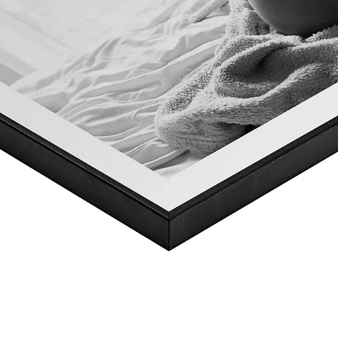 Reinders Bild Slim Frame Black - Legs Up, B x H: 40 x 50 cm - Nahaufnahme eines gerahmten Bildes, das ein weißes Bett mit einer flauschigen Decke zeigt, der Rahmen ist schwarz mit weißem Passepartout.