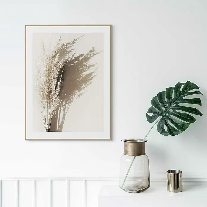 Reinders Bild Slim Frame Wood - Sunny Grass Bouquet, B x H: 30 x 40 cm - Kunstvoller Druck von getrocknetem Pampasgras in einem schlanken Rahmen, der eine moderne Wanddekoration ergänzt, neben einem dekorativen Blatt in einer Vase.