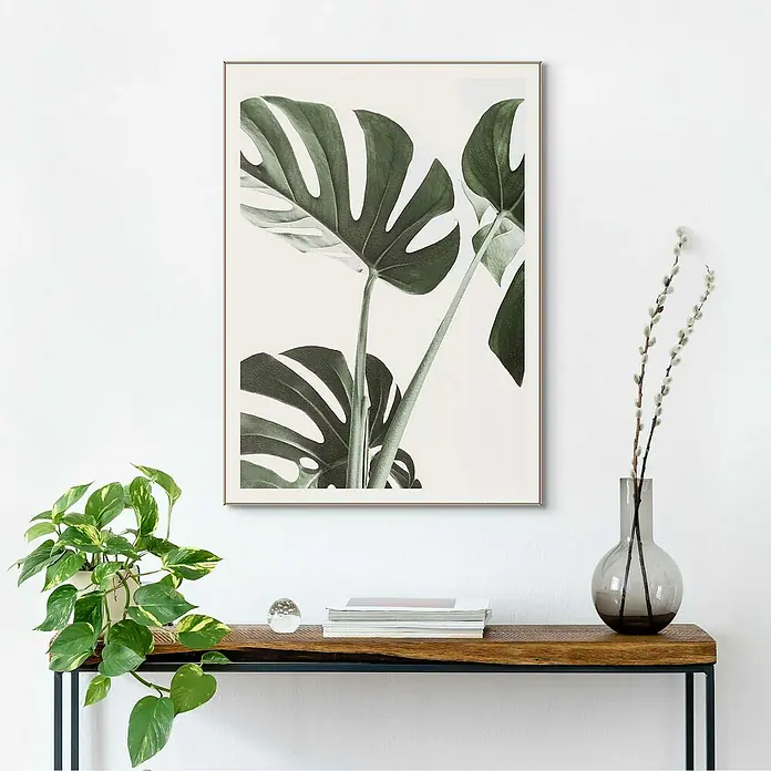 Reinders Bild Slim Frame Wood - Macro Monstera, B x H: 50 x 70 cm - Ein stilvolles Interieur mit einem gerahmten Monstera-Blattdruck, der an einer weißen Wand über einem Holztisch hängt.