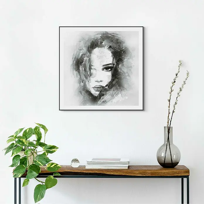 Reinders Bild Slim Frame Black - Water Colour Face, B x H: 50 x 50 cm - Schwarze und weiße Porträt-Wandkunst mit einem modernen Tisch, der mit einer Pflanze und einer Vase mit Blumen geschmückt ist.