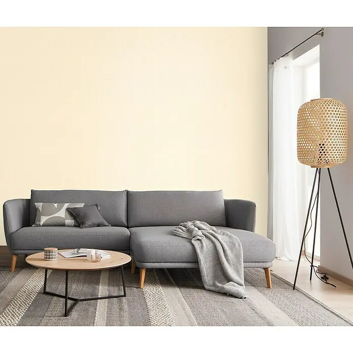 SCHÖNER WOHNEN-Farbe Trendstruktur Farbeffektputz Glimmerfarbe - Light Beige, Glitzernd, 2,5 l - Ein stilvolles Wohnzimmer mit einem grauen Ecksofa, einem runden Couchtisch und einer dekorativen Stehlampe, die eine gemütliche Atmosphäre schafft.