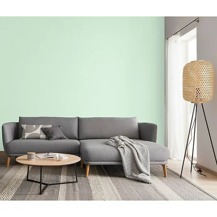 SCHÖNER WOHNEN-Farbe Trendstruktur Farbeffektputz Glimmerfarbe - Flash Mint, Glitzernd, 2,5 l - Ein graues Ecksofa mit einem Couchtisch und einer Stehlampe in einem hellen, modernen Wohnzimmer mit mintgrüner Wand.