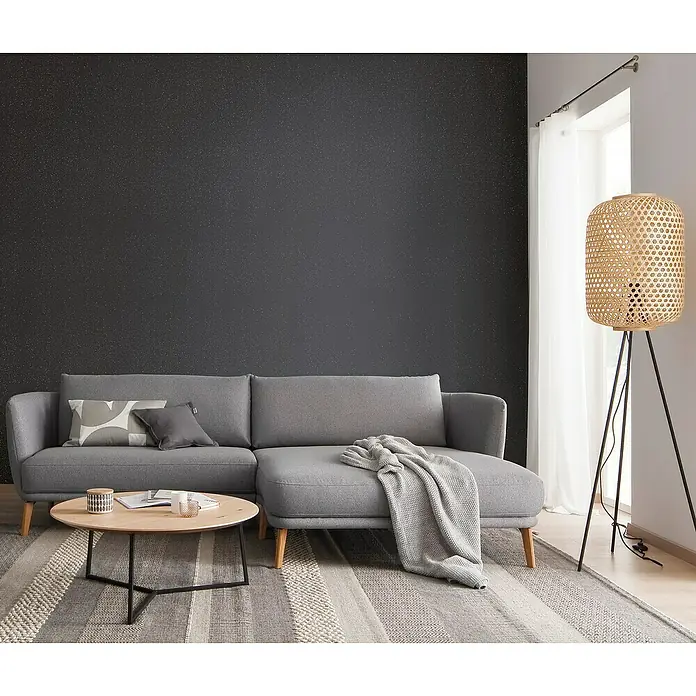 SCHÖNER WOHNEN-Farbe Trendstruktur Farbeffektputz Glimmerfarbe - Moonshine Black, Glitzernd, 2,5 l - Das graue Sofa mit Chaiselongue und Beistelltisch auf einem gemusterten Teppich vor einer dunklen Wand ist ein stilvolles Möbelstück.